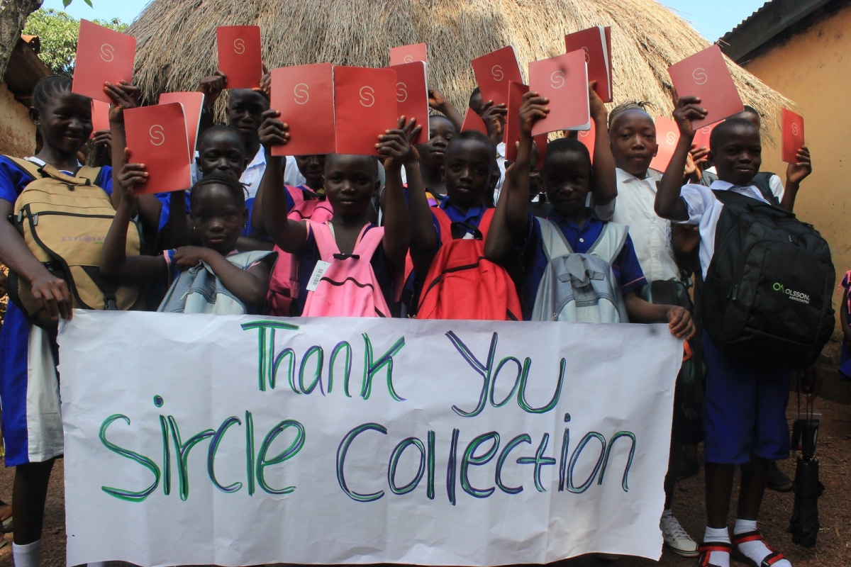 Pupils saying thank you with a banner and their school suppiles