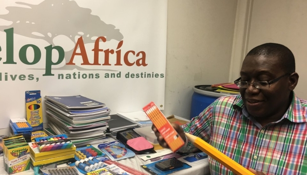 Sylvester, the CEO of Develop Africa with the donated school supplies