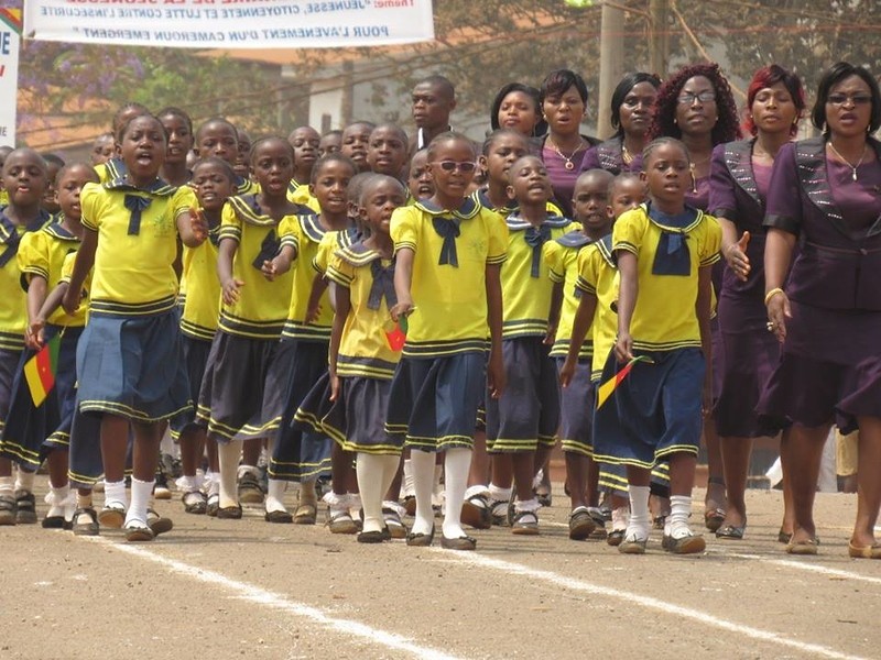 (c) Develop Africa. Cameroonian pupils and their teachers performing a match past.