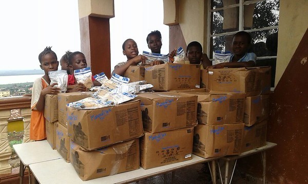 Supplies in cartons and kids standing behind it