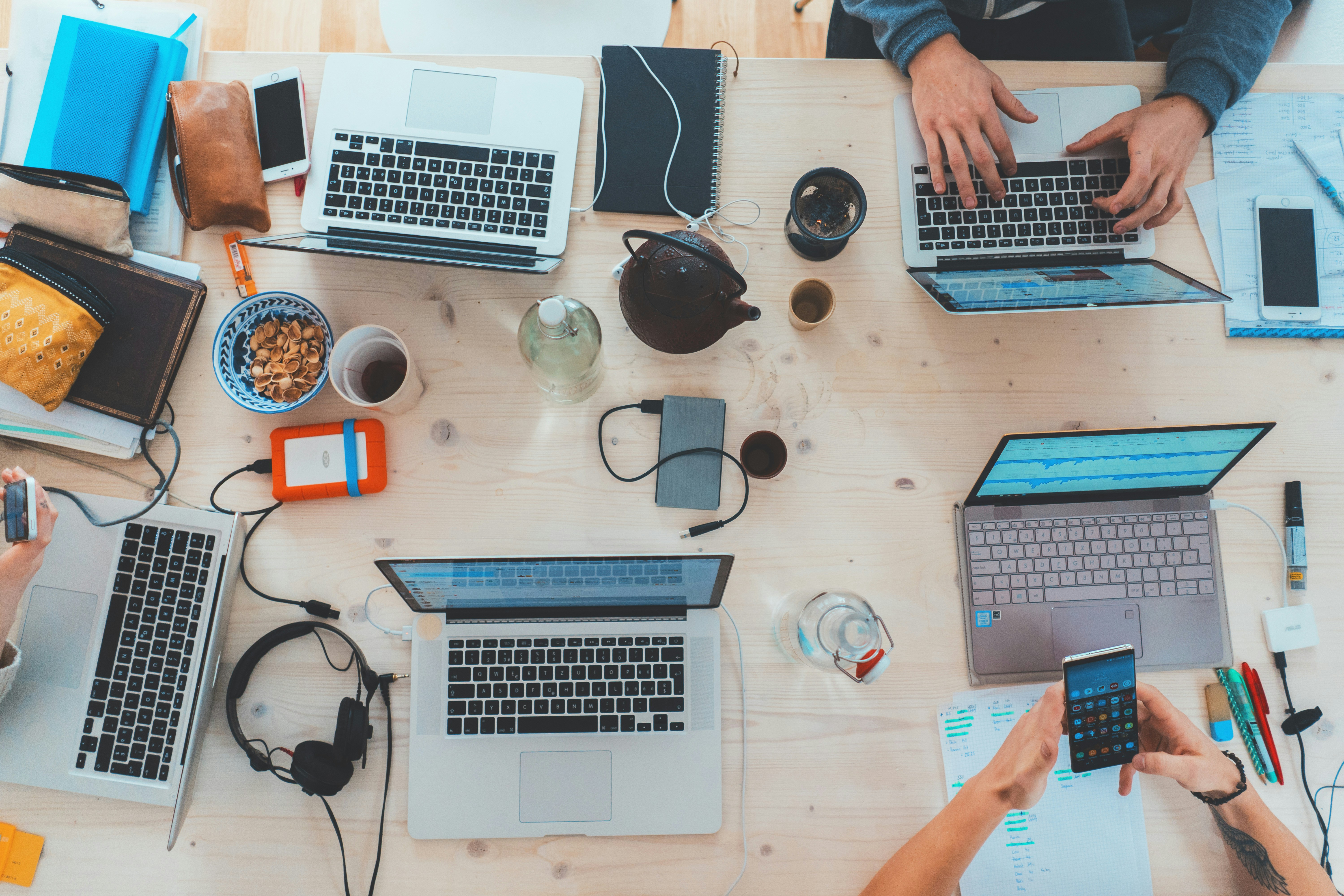 people sitting down near a table with assorted laptop computer